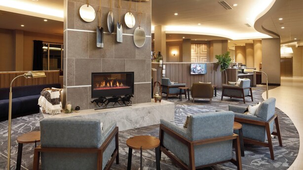A modern lobby with a fireplace, seating area, and a reception desk.