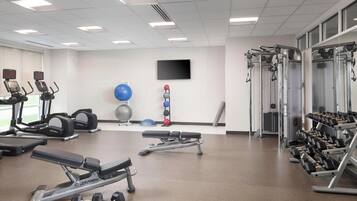 Een sportschool met cardioapparatuur, krachtapparaten en gewichten.