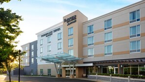 A Fairfield Inn & Suites by Marriott hotel with a modern design, featuring a covered entrance and a well-maintained outdoor area.