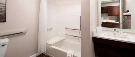 Un baño moderno con ducha a ras de suelo, inodoro y tocador con espejo.