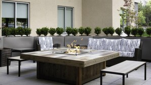 An outdoor seating area with a fire feature, a sofa, and a table. - TownePlace Suites by Marriott Louisville Northeast (Louisville)