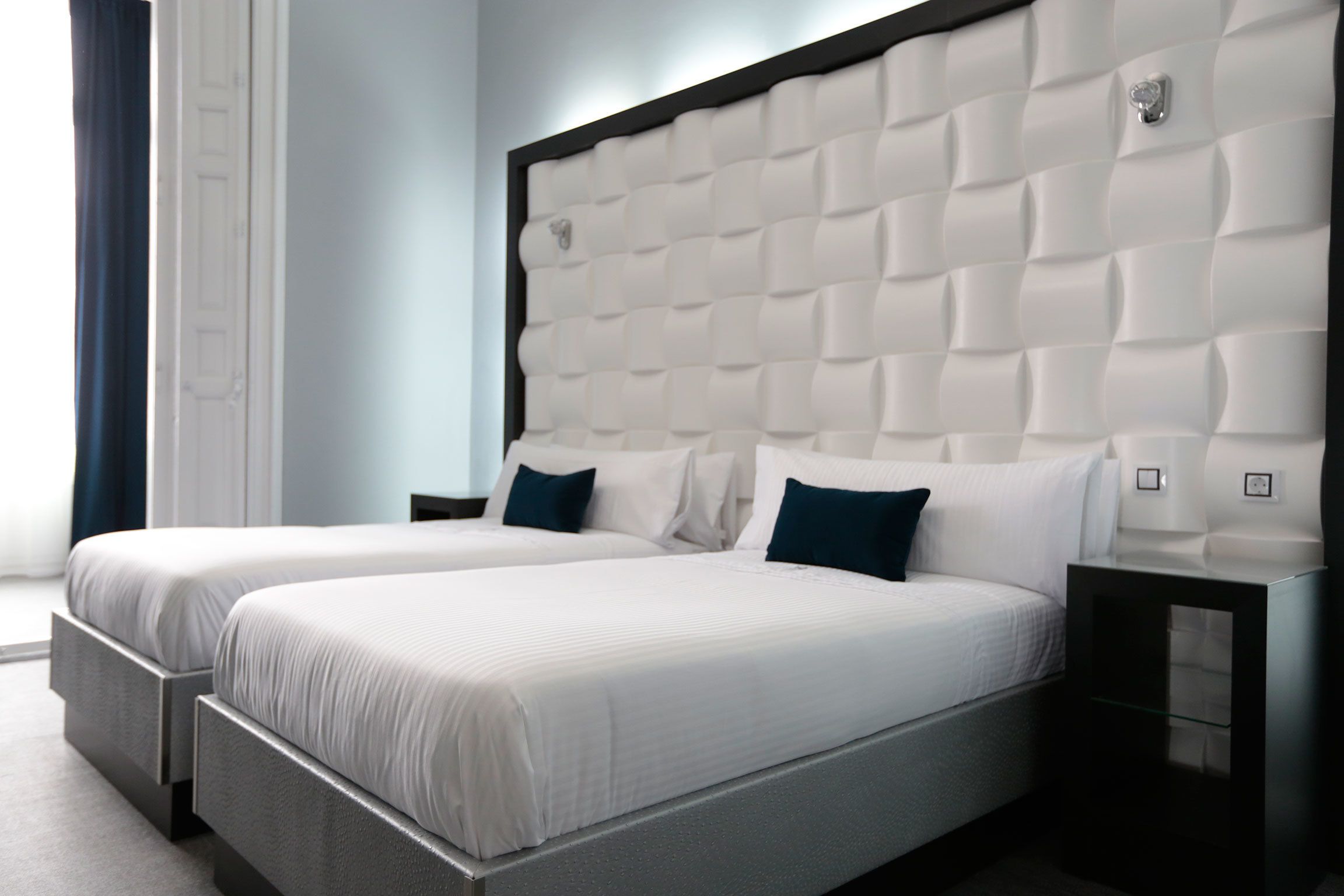 A double bed with a tufted headboard, two bedside tables, and a nightstand.