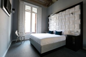 Quarto moderno com uma cama grande, uma cadeira e uma cabeceira singular.