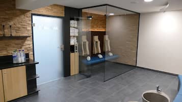 Een moderne badkamer met een glazen wand, een houten muur, een blauwe bank en een wastafel met spiegel.