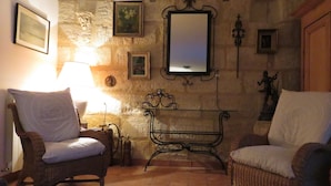 Una habitación acogedora con sillones de mimbre, una mesita y un espejo en la pared.