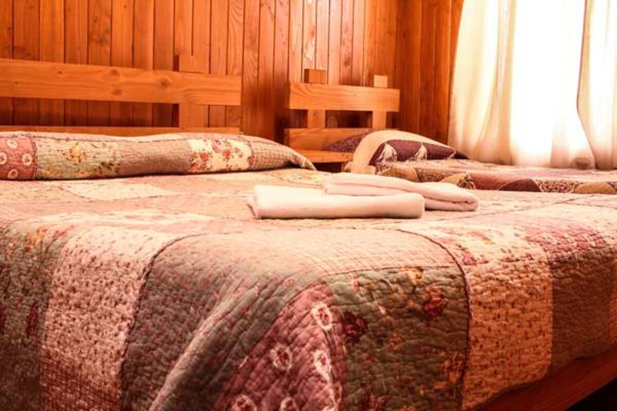 Una cama de madera con colcha acolchada y almohadas.