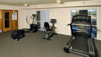 A fitness room with three treadmills, a stationary bike, and a rowing machine.
