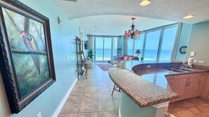 A spacious kitchen with a large island, a dining area with a view of the ocean, and a living room with a large window overlooking the sea.