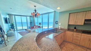A spacious kitchen with a large island, a dining area with a view, and a living room with a view of the ocean.