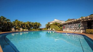 Une piscine d’un bleu éclatant, avec des chaises longues et des palmiers.