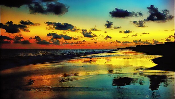 Una playa con un atardecer y olas del océano.