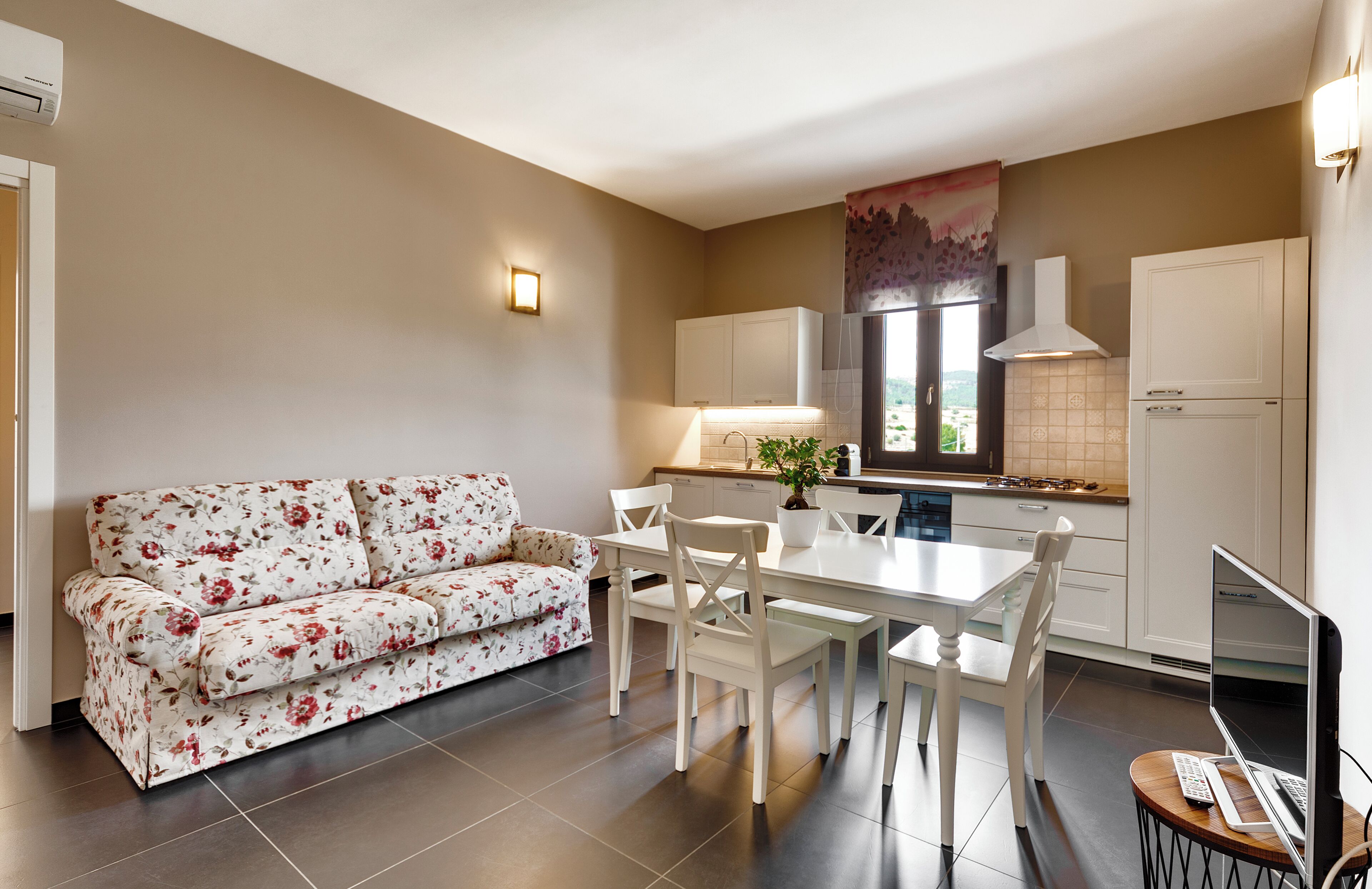 Une cuisine moderne avec des meubles blancs, une table à manger et un canapé à motifs floraux.