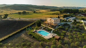 Vista aérea de una propiedad con piscina, varias edificaciones y vegetación circundante.