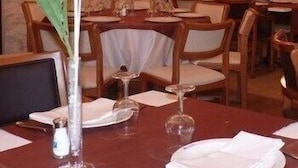 Un comedor con mesas dispuestas para el servicio, una araña y obras de arte en las paredes.
