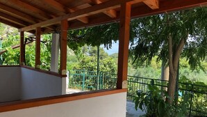 A covered outdoor area with a wooden ceiling, a white wall, and a green metal fence.