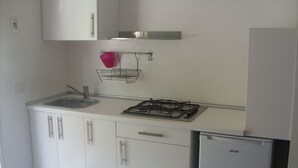 A kitchen with white cabinets, a gas stove, a sink, and a refrigerator.