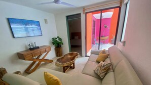 A living room with a sofa, a coffee table, a wooden side table, a television, and a plant.