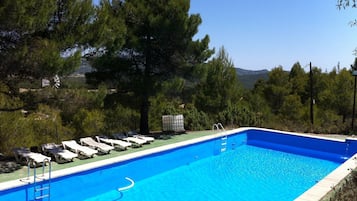 A rectangular swimming pool with a clear blue water, surrounded by lounge chairs and a ladder.