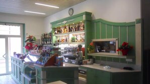 Een bar met groene kasten, een klok en verschillende flessen en glazen.