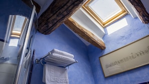 A bathroom with a skylight, a towel rack, and a framed artwork on the wall.