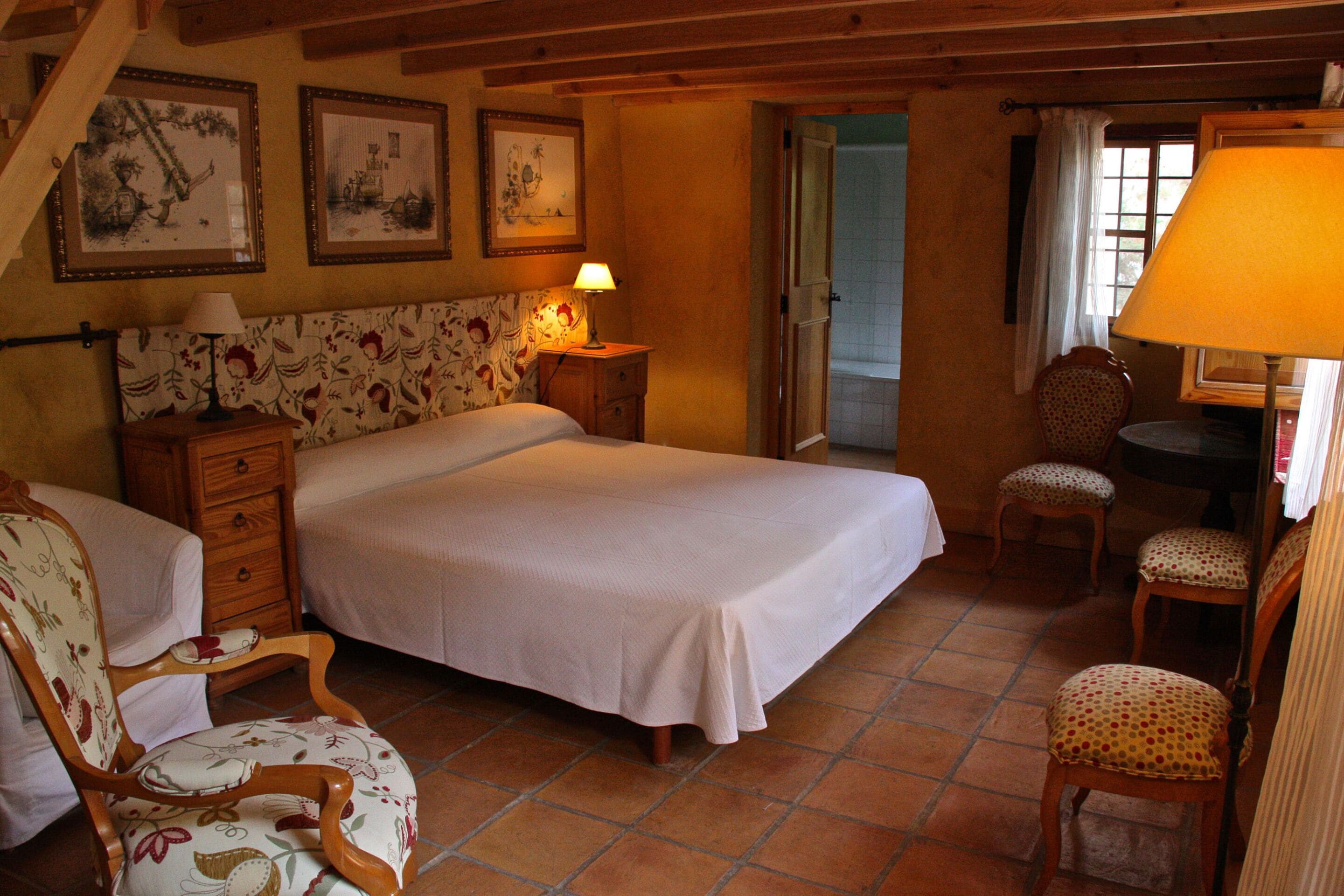 Une chambre à coucher avec un lit, des tables de chevet en bois, une chaise et un bureau.