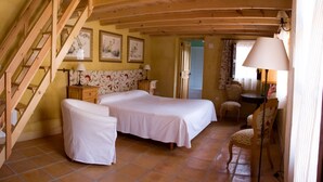 A bedroom with a wooden staircase, a double bed, two bedside tables, a chair, and a lamp.