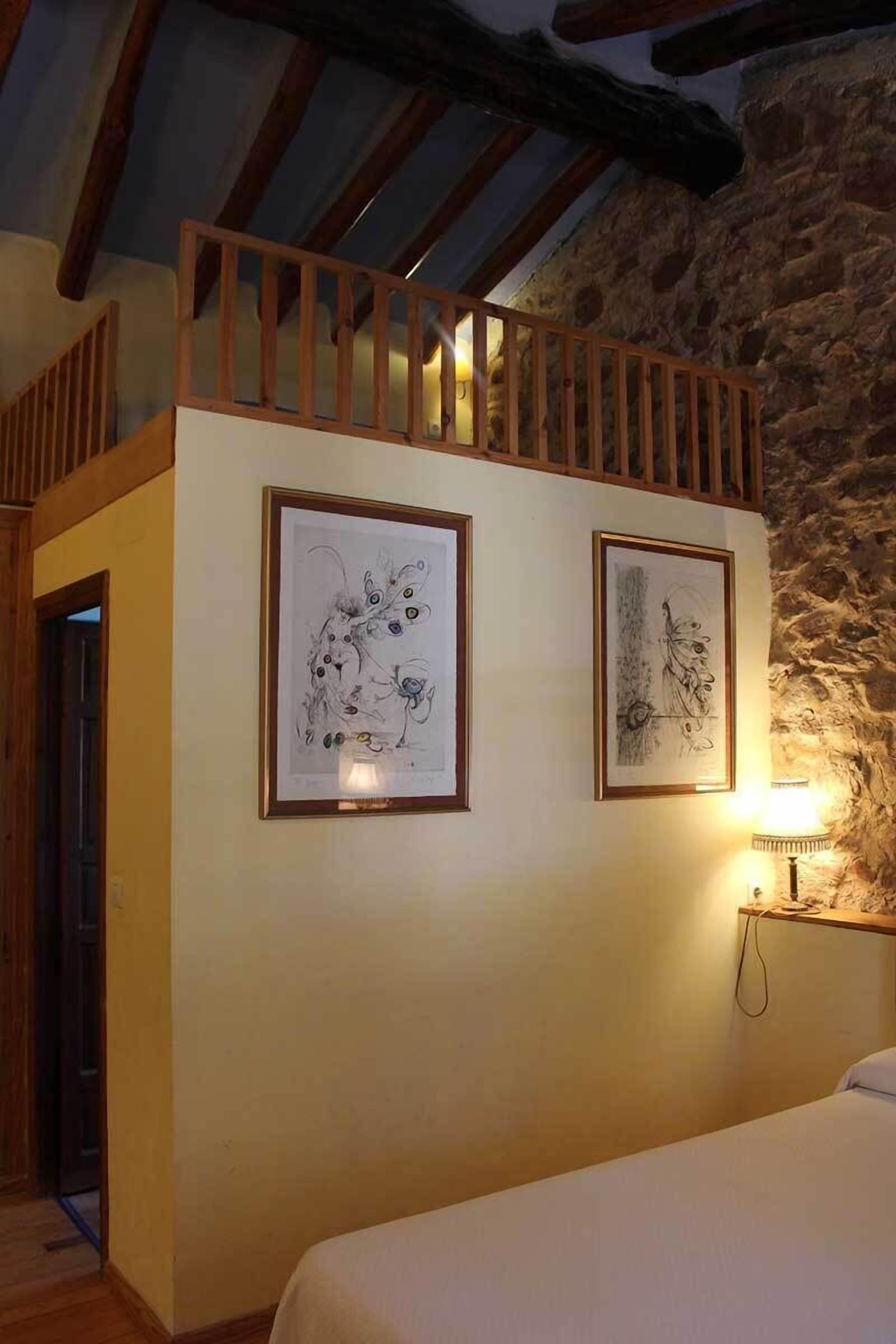 Un dormitorio con techo de madera, una cama y dos obras de arte enmarcadas en la pared.