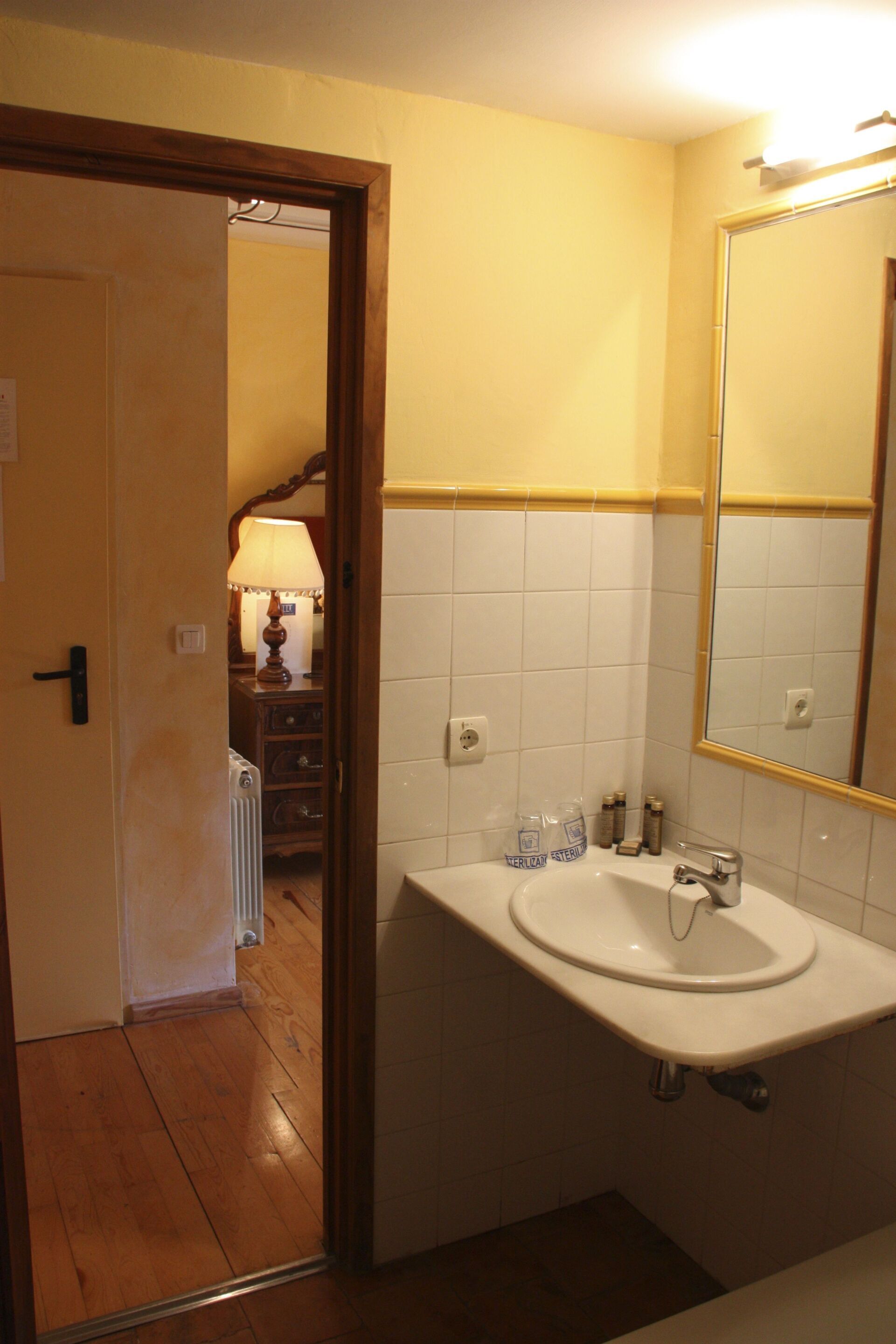 A bathroom with a white sink, mirror, and wooden door.