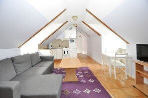 A compact living space with a sofa, dining table, and kitchenette. - Boende Visby (Visby)