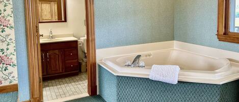 A bathroom with a freestanding bathtub, wooden vanity, and a mirror.