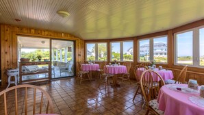 A restaurant with wooden walls and large windows, offering views of the landscape. - Rose Farm Inn (Block Island)
