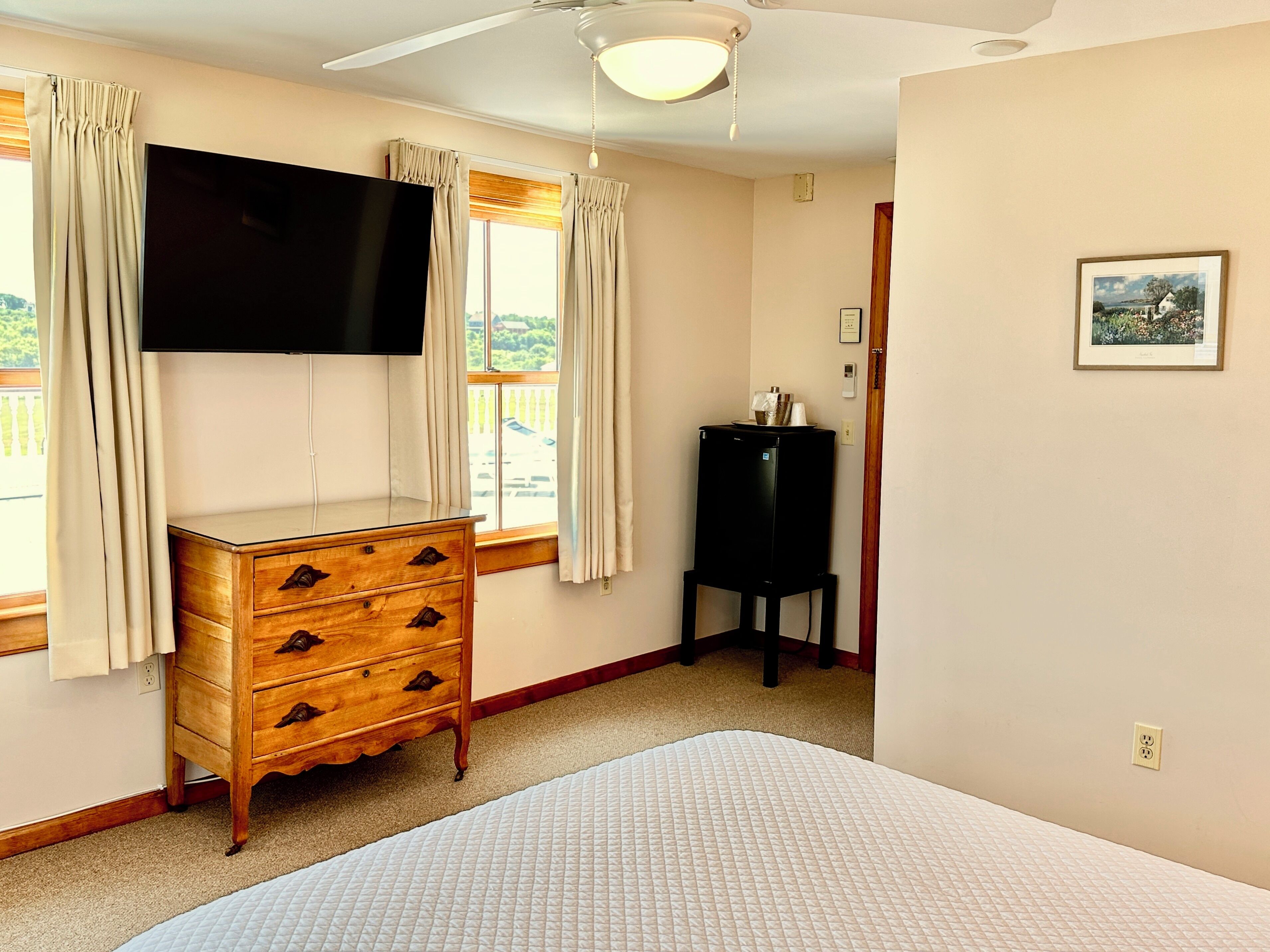 A bedroom with a bed, wooden dresser, TV, and a water dispenser.