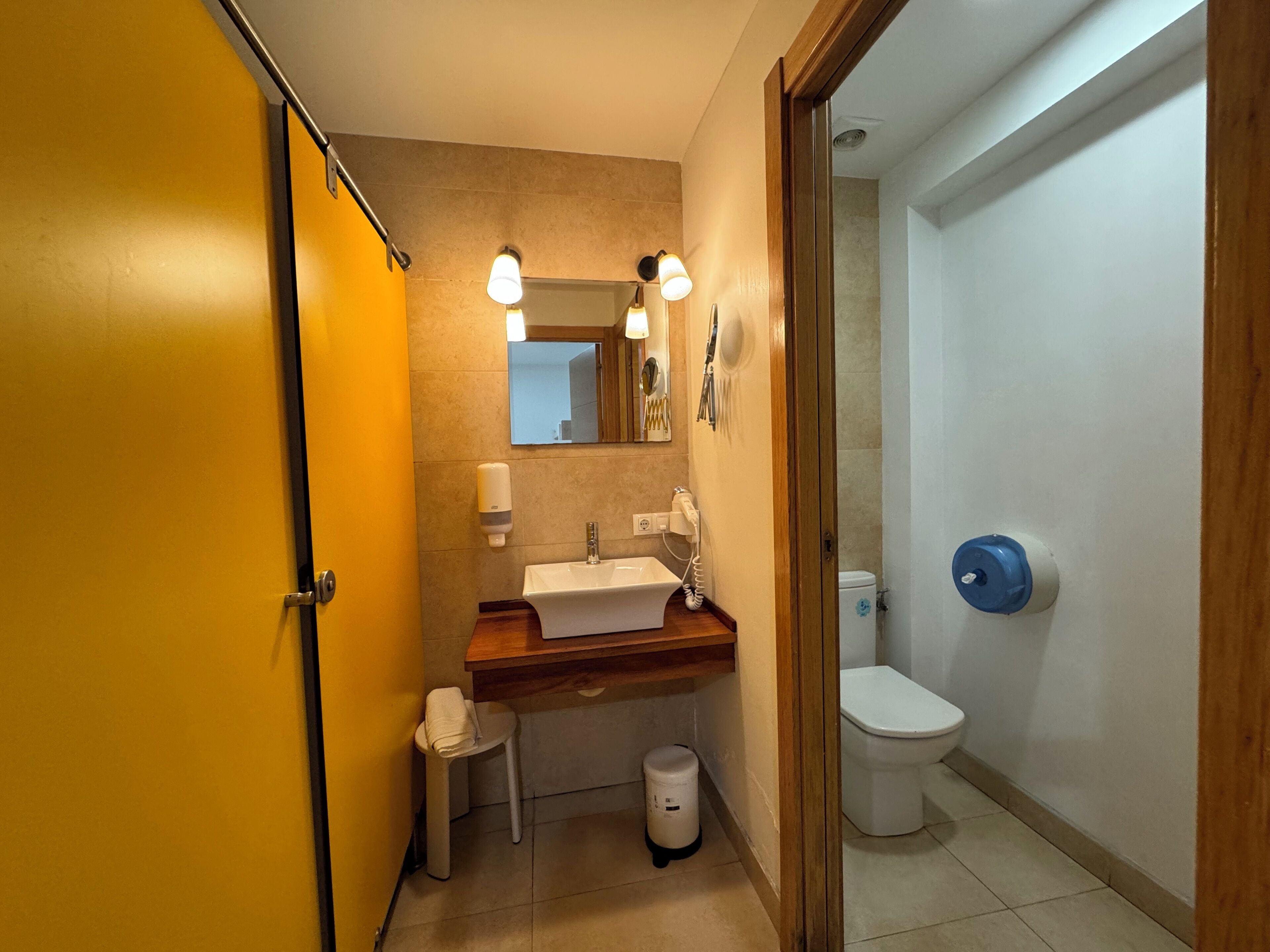 A compact bathroom with a sink, mirror, and toilet.