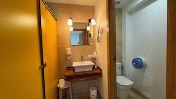 A compact bathroom with a sink, mirror, and toilet.