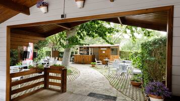 Un espace extérieur aménagé en terrasse, avec des tables et des chaises en bois, des plantes en pot et une clôture en bois.