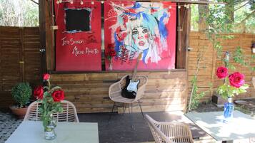 Un espacio de estar al aire libre con madera, que incluye una mesa, sillas y una guitarra.