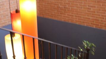 Una escalera con barandilla, un muro de ladrillo y una ventana con luz natural.
