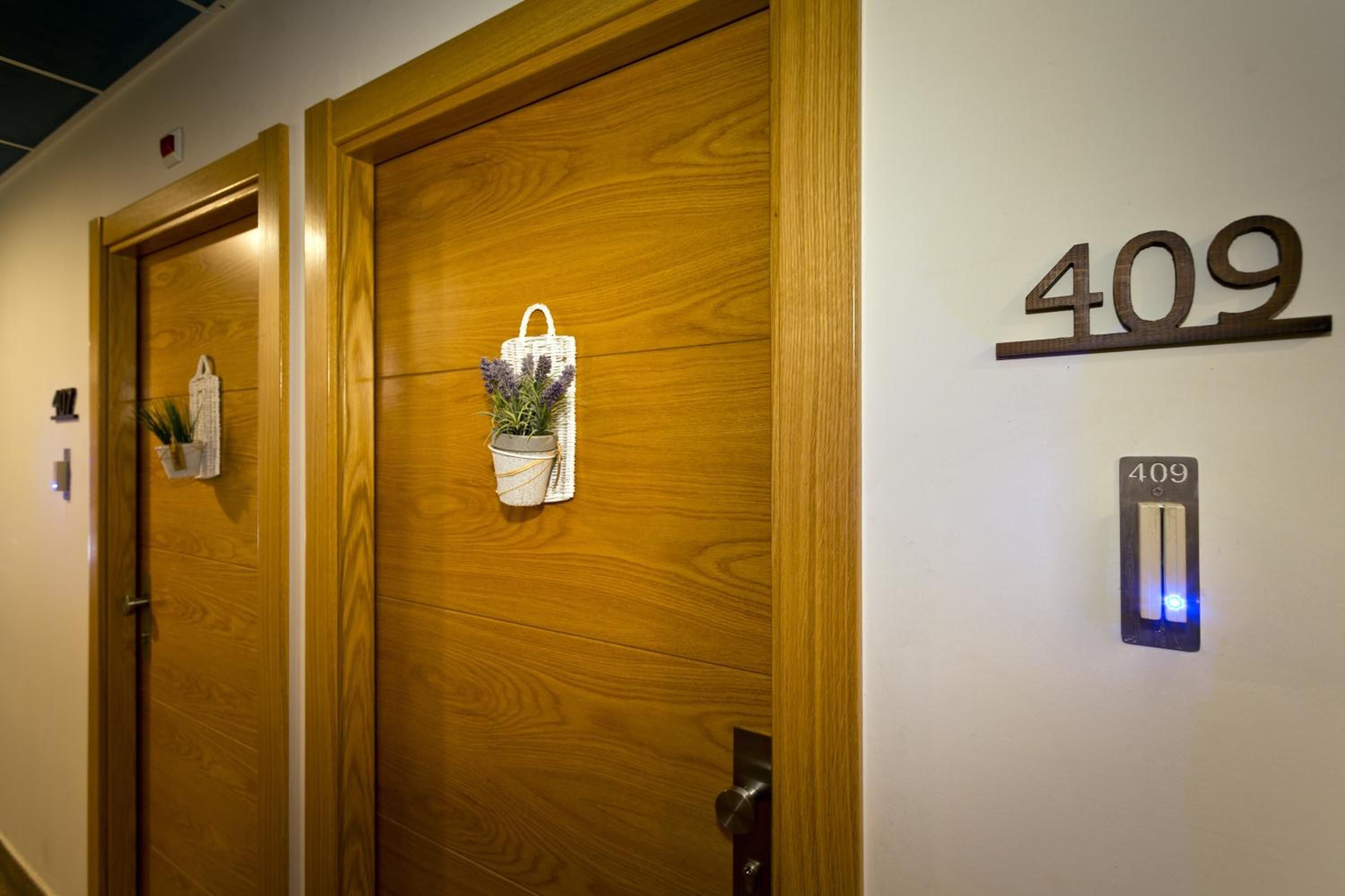 A hotel entrance with wooden doors, a number 409 sign, and a light switch on the wall.