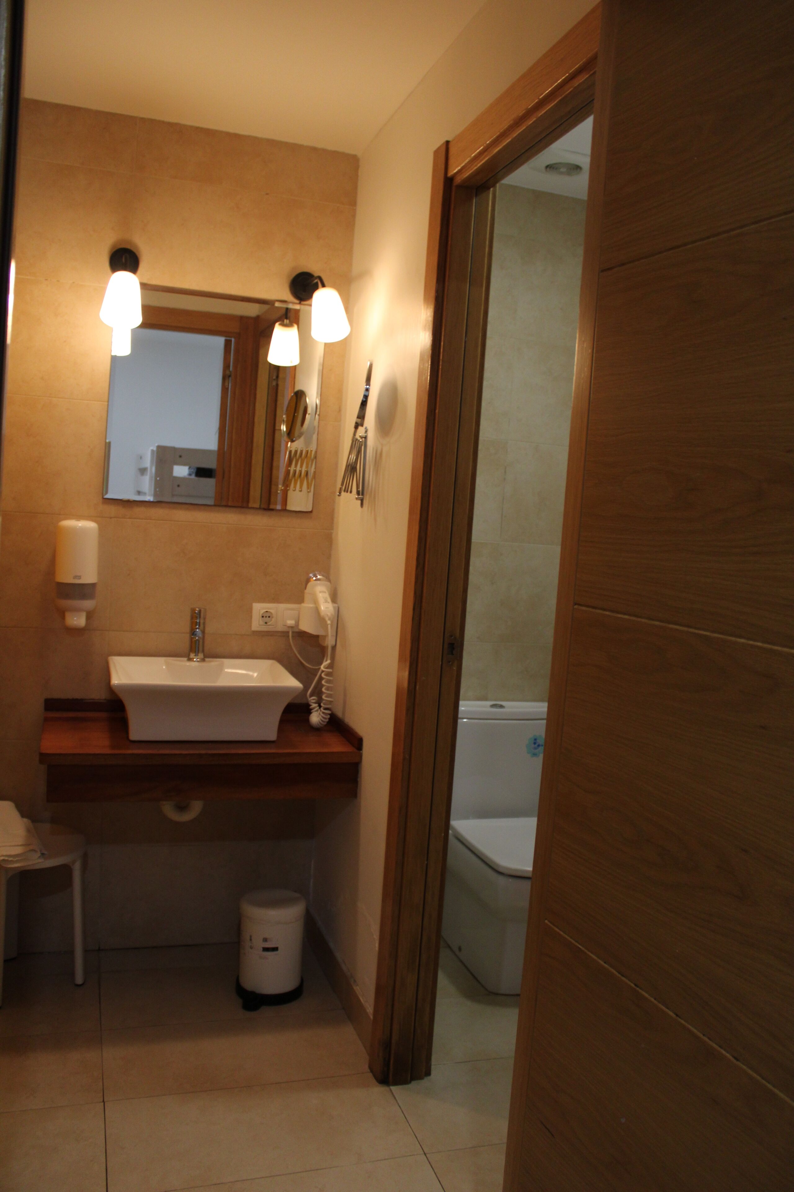 A bathroom with a wooden vanity, a sink, a mirror, and a toilet.