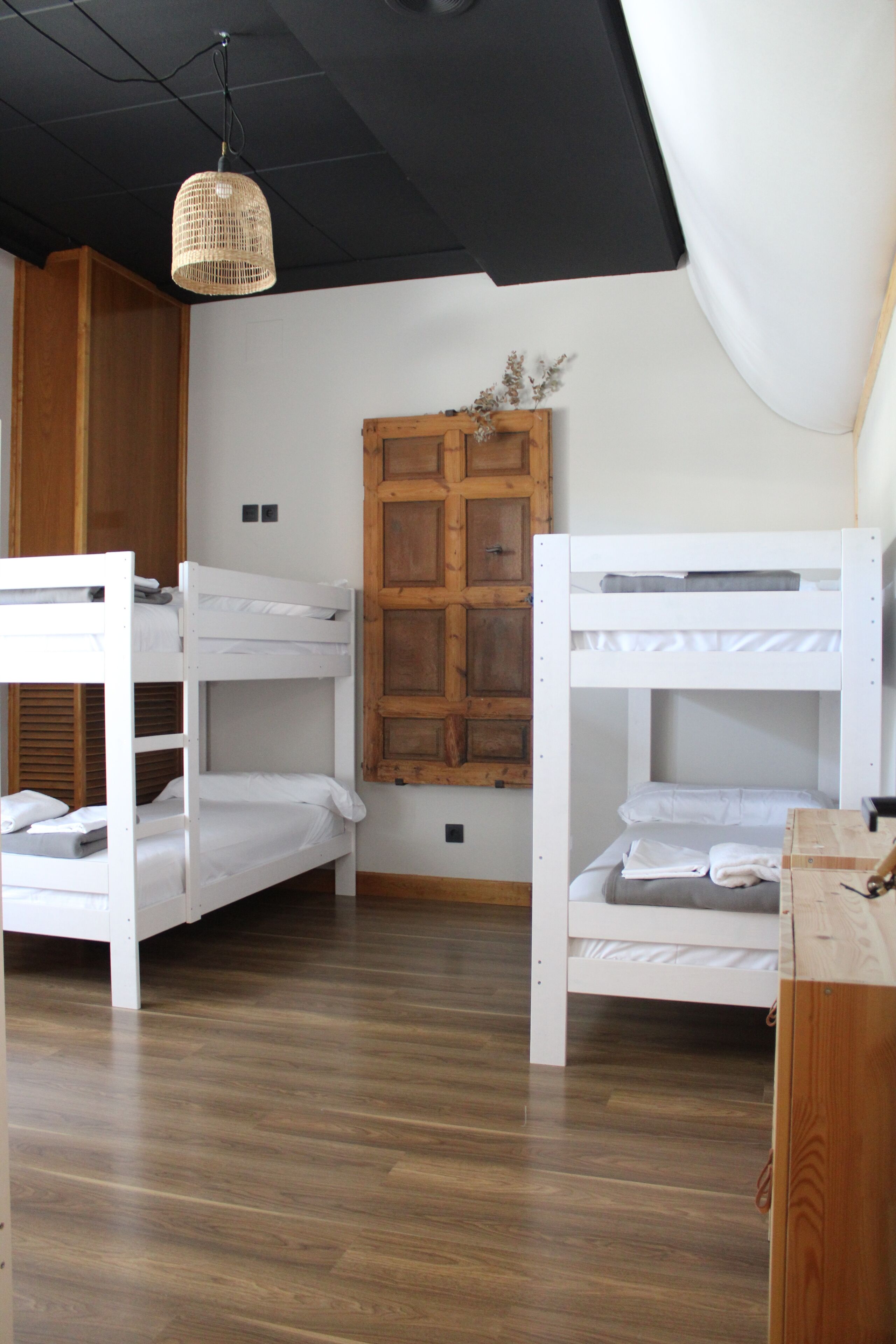 A room with bunk beds, wooden wardrobe, and a hanging light fixture.