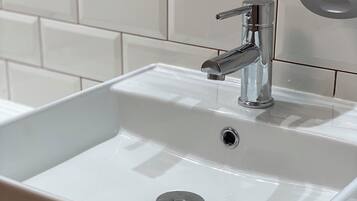 A white bathroom sink with a chrome faucet and a drain.