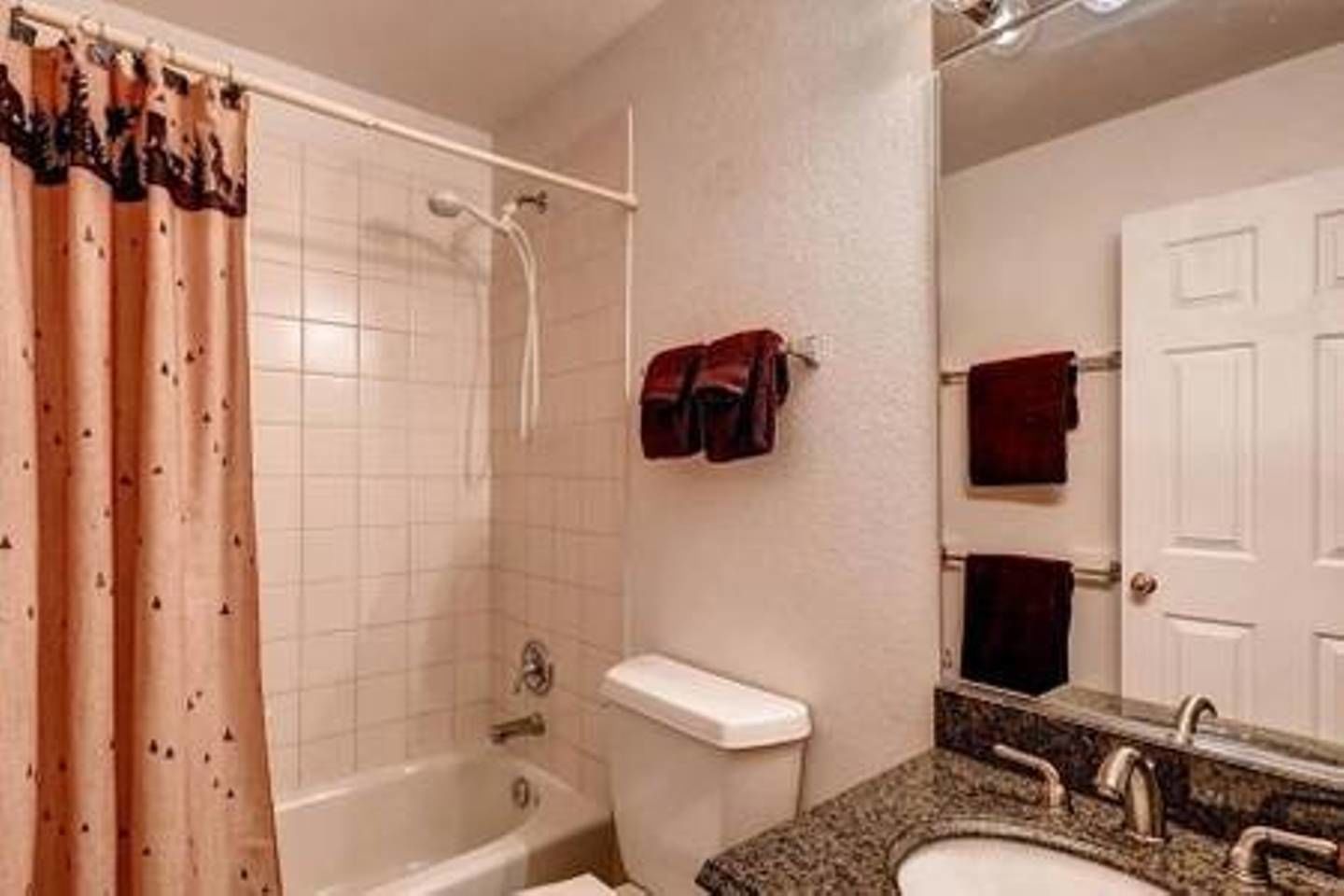 Un baño con ducha, inodoro, lavamanos y espejo.