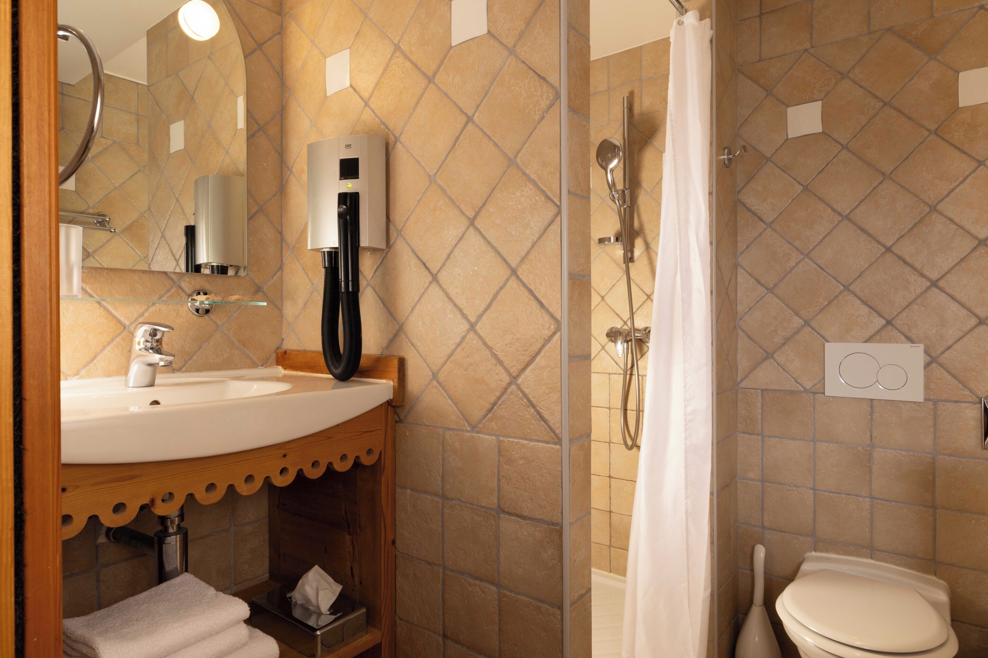 Ein Badezimmer mit Waschbecken, Spiegel, Handtuchhalter, Dusche und Toilette.