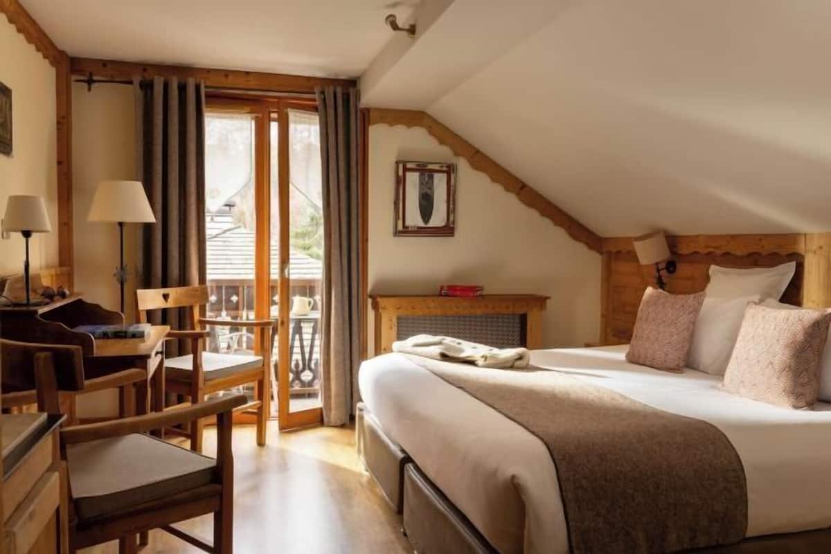 Ein Schlafzimmer mit Bett, Schreibtisch, Stuhl, Kamin und Balkon.