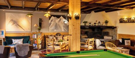 A cozy room with a pool table, wooden furniture, and a fireplace.