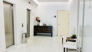 A clean, modern hallway with a reception desk, a bench, and a door. - Alameda Downtown Apartment 1204 (Mexico City)