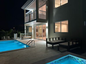 A two-story building with a swimming pool, outdoor seating, and a covered patio area. - Checkers Vacation Homes (Providenciales)