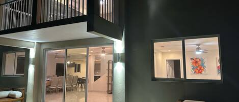 Un interior espacioso con balcón, comedor y sala de estar con un ventanal grande y obras de arte.
