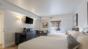 A hotel room with two beds, a desk with a chair, a flat-screen TV, and a window with a view of trees. - Managed by Park City Lodging-Deluxe Condo-Walking Distance to PC Mtn Town Lift (Park City)