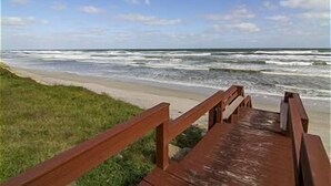 A wooden boardwalk leading to a beach with waves crashing onto the shore.